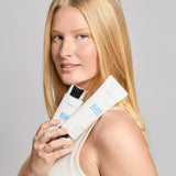 Woman holding two skincare colorescience spf 50 no show  products against a gray background